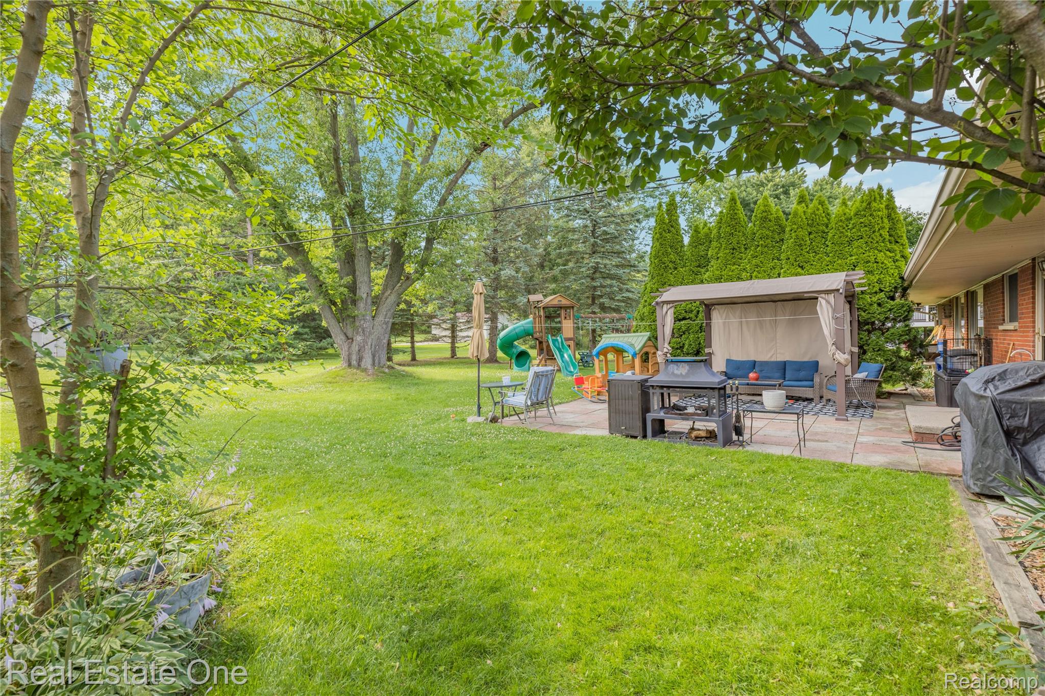 2810 Walbridge Drive Rochester, MI 48307 - Photo 39 of 58 Expansive backyard featuring a lush lawn, mature trees, and a spacious stone patio