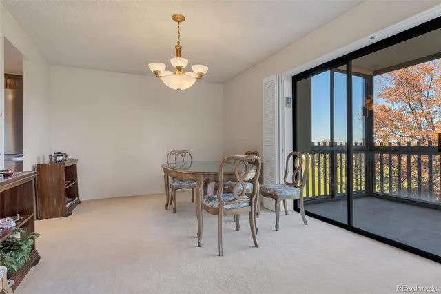 a view of a dining room with furniture a chandelier and large windows