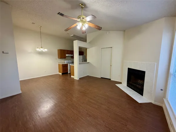 an empty room with wooden floor fireplace and windows