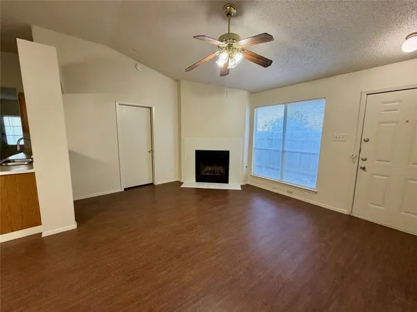 an empty room with wooden floor chandelier and windows