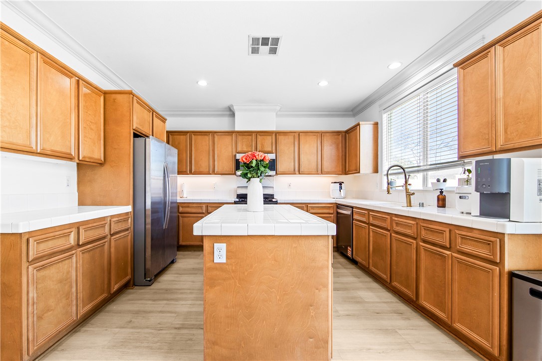 6310 Cosmos Street Eastvale, CA 92880 - Photo 21 of 71 a kitchen with stainless steel appliances granite countertop a sink counter space cabinets and a large window