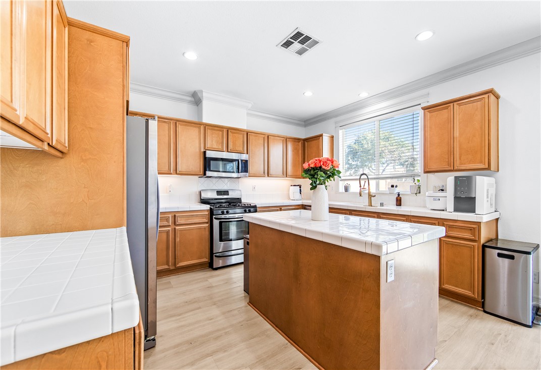 6310 Cosmos Street Eastvale, CA 92880 - Photo 22 of 71 a kitchen with stainless steel appliances granite countertop a stove top oven a sink dishwasher and a refrigerator