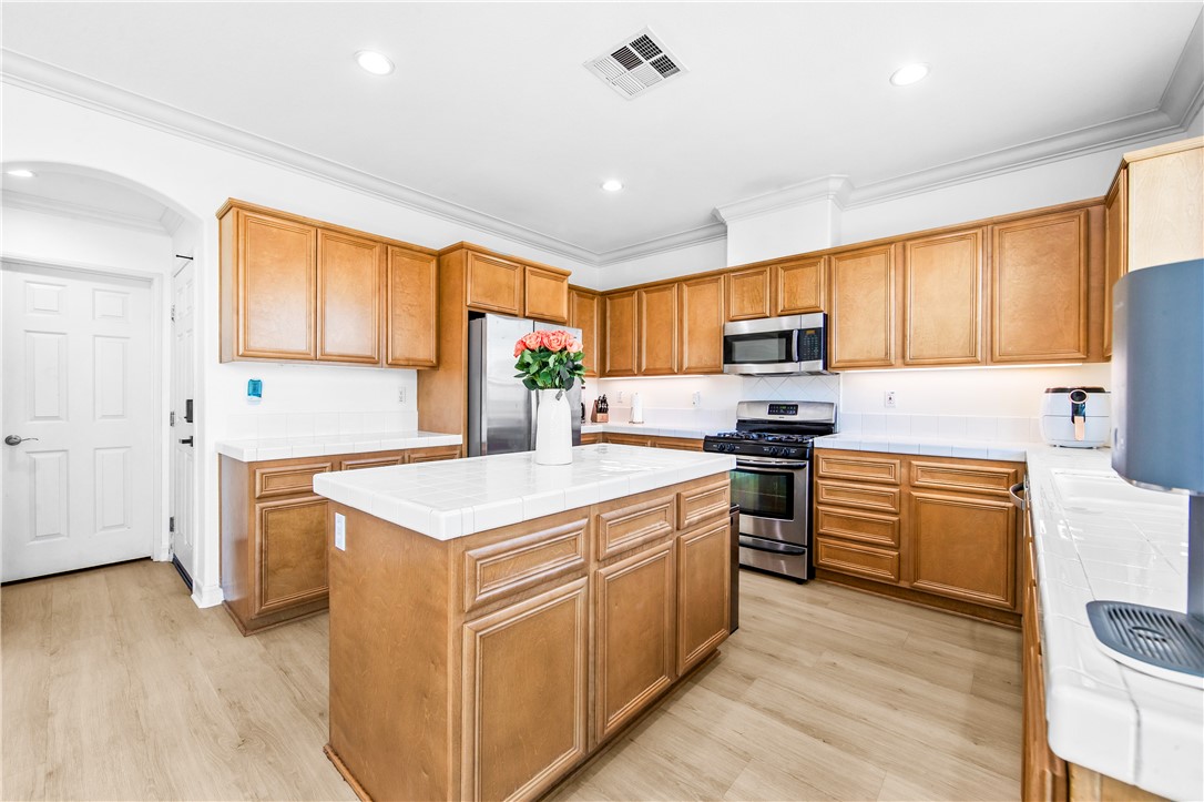 6310 Cosmos Street Eastvale, CA 92880 - Photo 23 of 71 a kitchen with stainless steel appliances granite countertop a stove top oven a sink dishwasher and a refrigerator with wooden floor