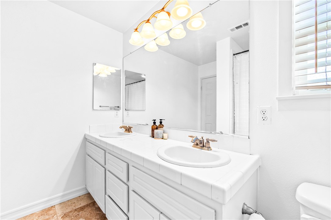 6310 Cosmos Street Eastvale, CA 92880 - Photo 45 of 71 a bathroom with a sink a toilet and a mirror