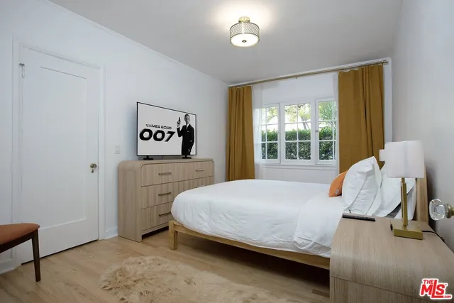 a bedroom with a bed and a flat tv screen on dresser