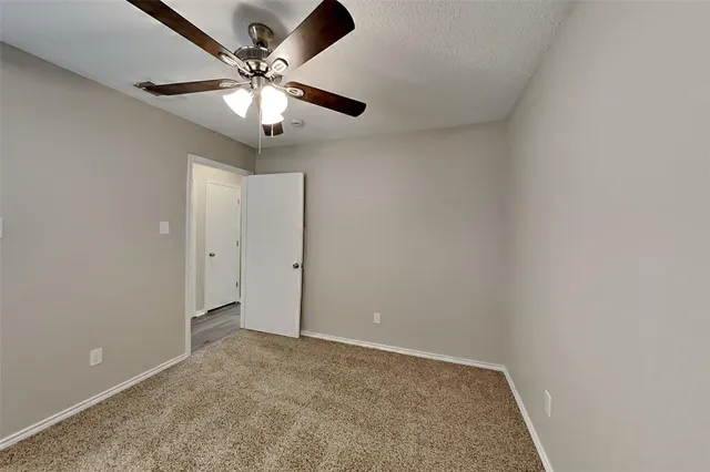 an empty room with a chandelier fan and closet