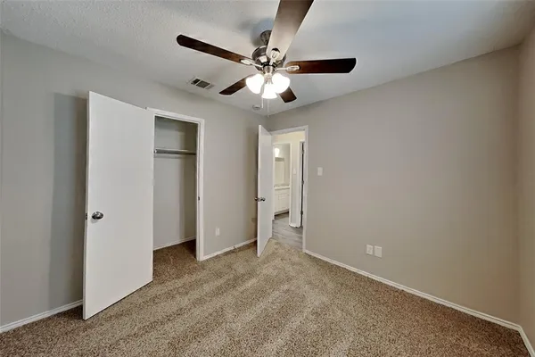 an empty room with closet and a ceiling fan
