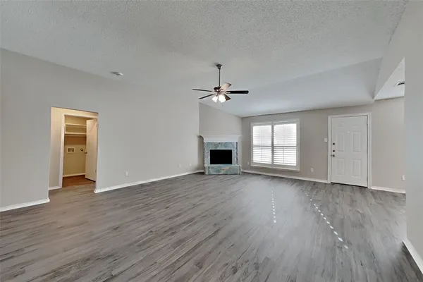 an empty room with wooden floor fireplace and windows