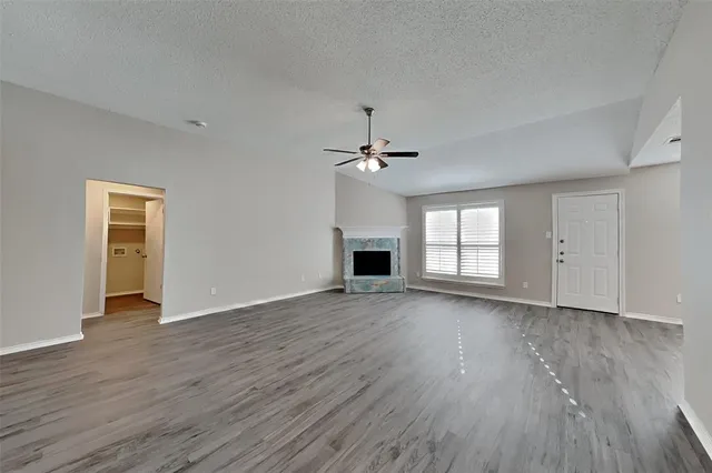 an empty room with wooden floor fireplace and windows