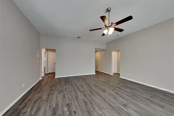 a view of an empty room with window and wooden floor
