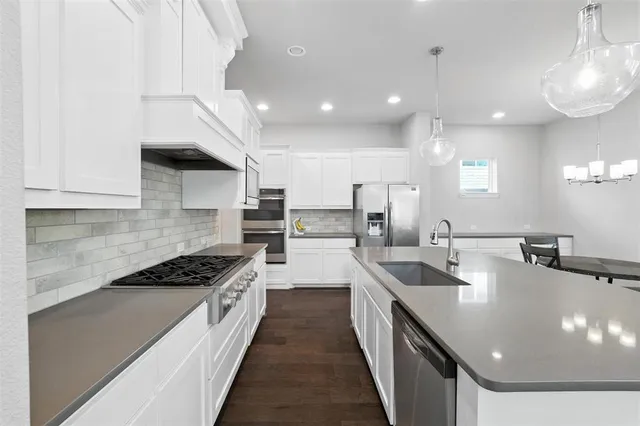 a kitchen with stainless steel appliances granite countertop a sink a stove and a refrigerator