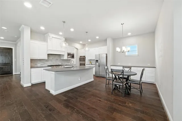 a kitchen with stainless steel appliances granite countertop a kitchen island hardwood floor sink stove dining table and chairs