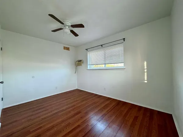a view of a big room with wooden floor ceiling fan and windows