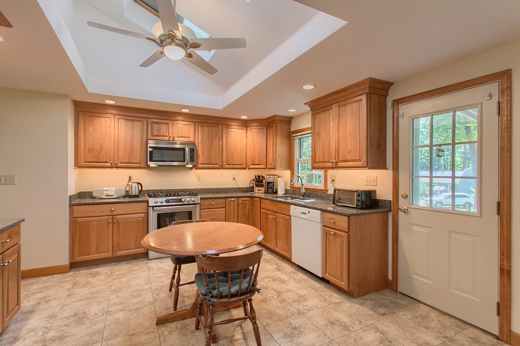 24 Newton Road Westminster, MA 01473 - Photo 5 of 30 a kitchen with stainless steel appliances granite countertop a stove top oven a sink dishwasher a dining table and chairs with wooden cabinets
