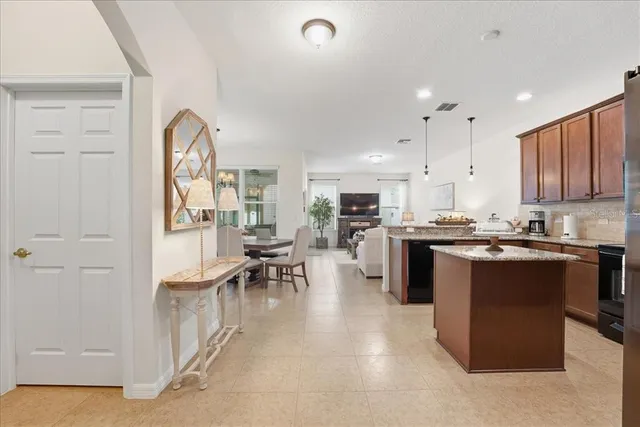 a kitchen with stainless steel appliances kitchen island granite countertop a stove top oven a sink a dining table and chairs