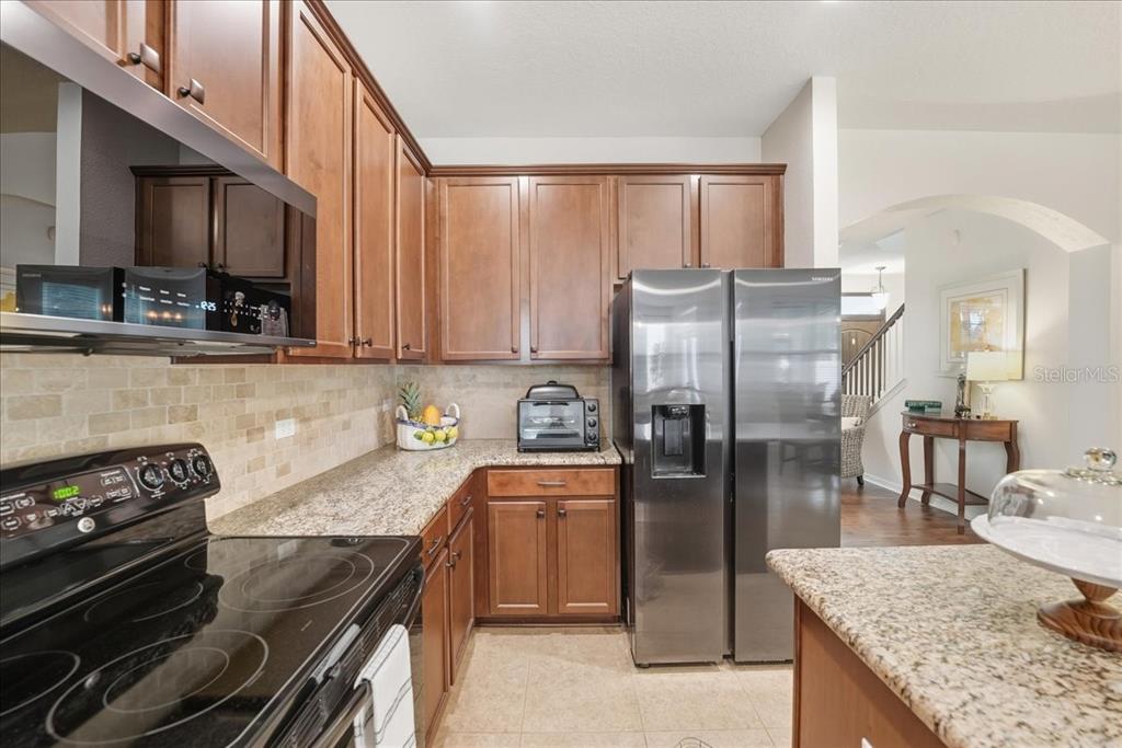 11675 Snail Kite Way Windermere, FL 34786 - Photo 15 of 46 a kitchen with granite countertop a refrigerator stove and oven