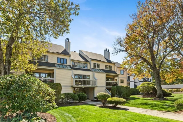 a front view of a house with garden and trees