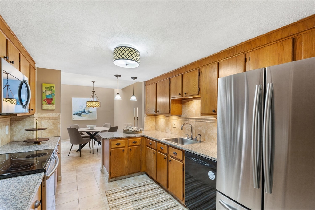 1100 Salem Street, Unit 58 Peabody, MA 01960 - Photo 13 of 36 a kitchen with stainless steel appliances granite countertop a refrigerator and a stove top oven