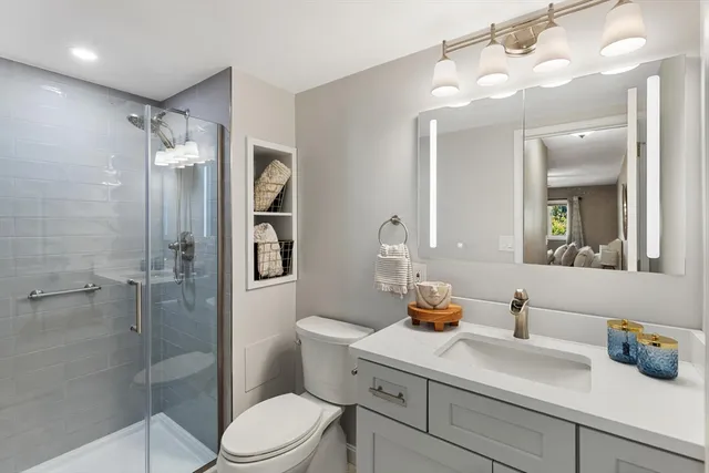 a bathroom with a sink vanity granite toilet and shower