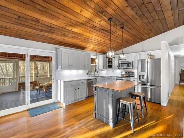 a kitchen with stainless steel appliances granite countertop a table chairs refrigerator and sink