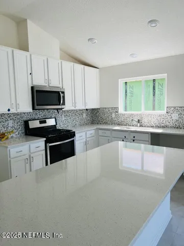 a kitchen with granite countertop a stove a sink and a microwave