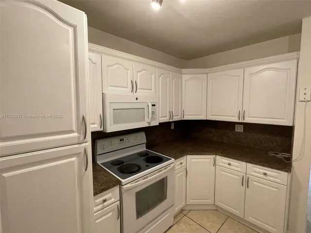 a kitchen with granite countertop white cabinets and white appliances