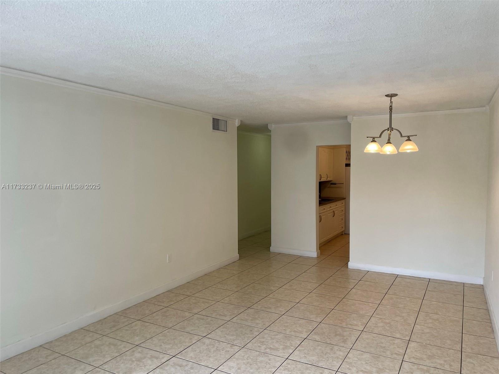 1950 West 54th Street, Unit 112 Hialeah, FL 33012 - Photo 9 of 27 an empty room with chandelier fan and kitchen view