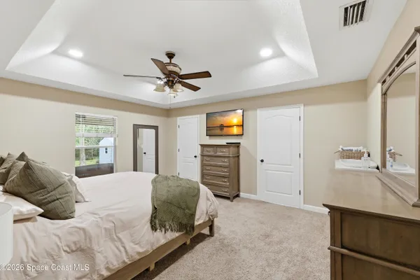 a bedroom with a bed a dresser and a chandelier