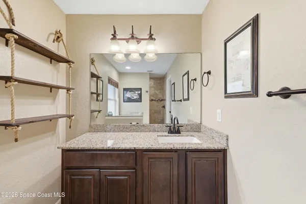 a bathroom with a granite countertop sink a mirror and shower