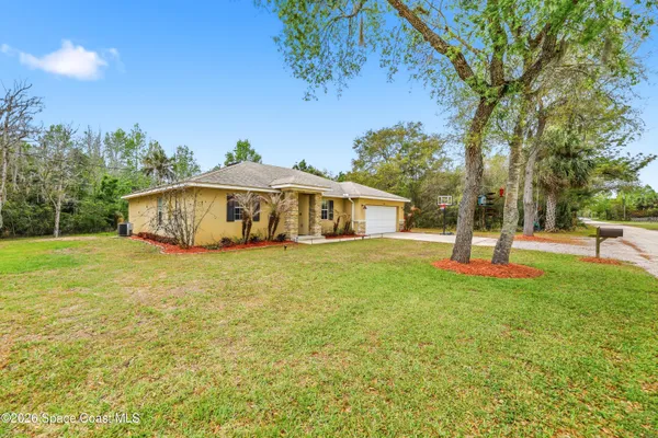 a front view of a house with yard and tree s