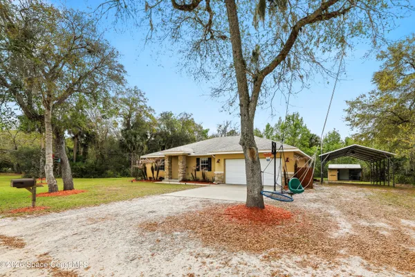 a front view of a house with a yard and trees