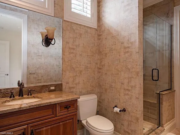 a bathroom with a granite countertop toilet a sink and mirror