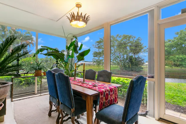 a view of a dining room with furniture a potted plant and a floor to ceiling window