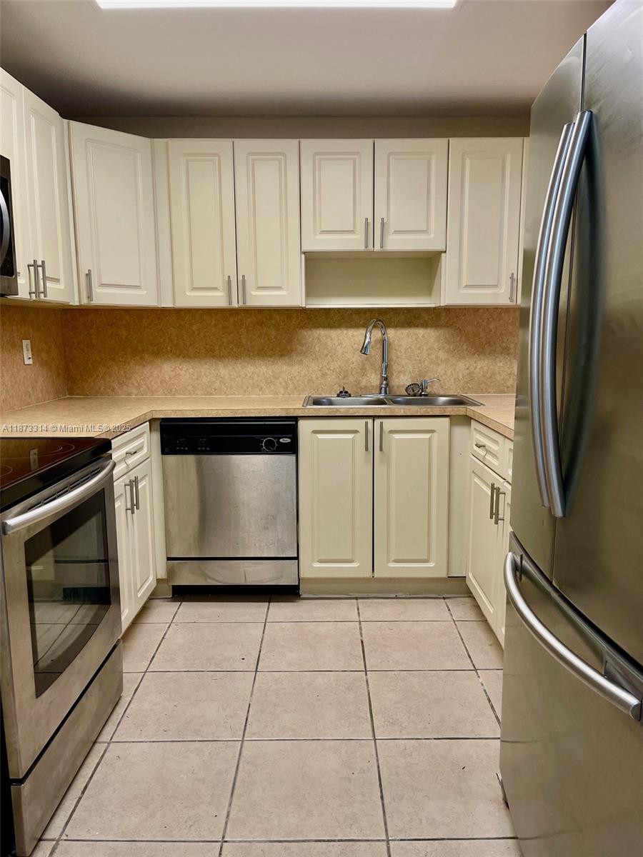 7000 Northwest 186th Street, Unit 4121 Hialeah, FL 33015 - Photo 9 of 27 a kitchen with granite countertop a stove a sink and a refrigerator with white cabinets