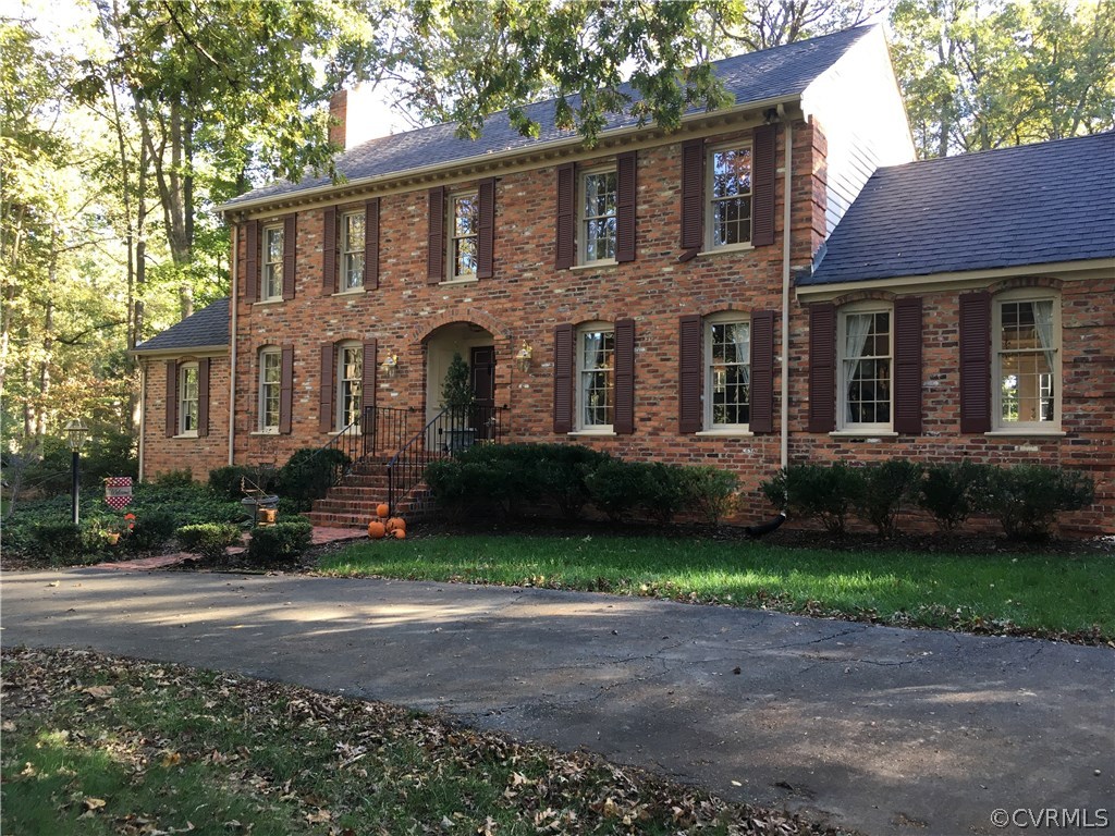 a front view of a house with a garden and trees