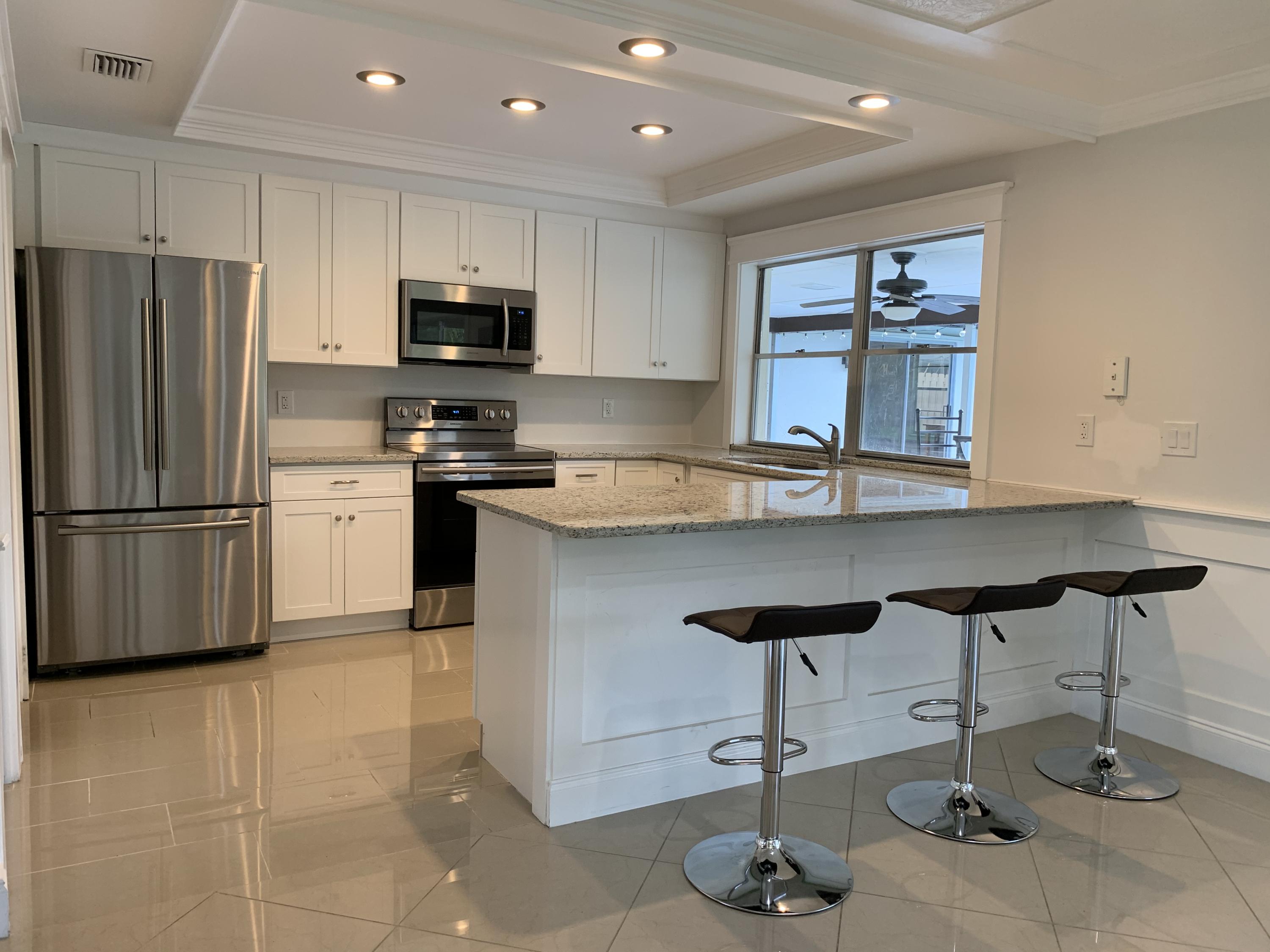 a kitchen with granite countertop a stove refrigerator and microwave