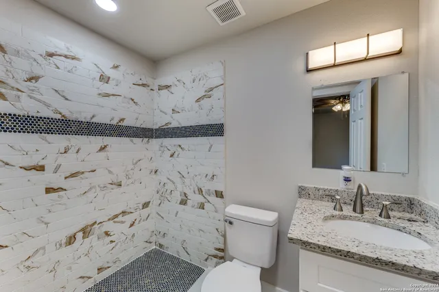 a bathroom with a granite countertop sink a toilet and shower curtain