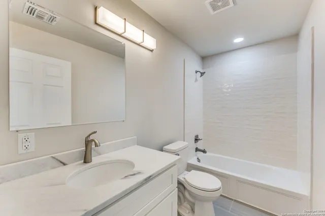 a bathroom with a granite countertop sink a toilet and a bathtub