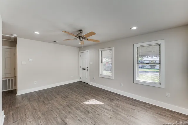 a view of an empty room with a window and wooden floor