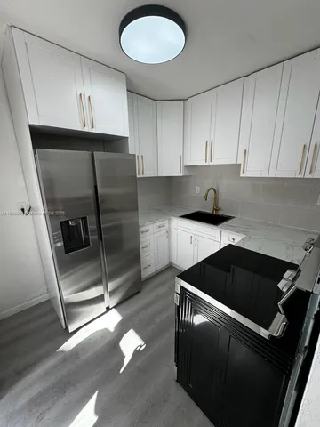 a kitchen with granite countertop a refrigerator a sink and a stove