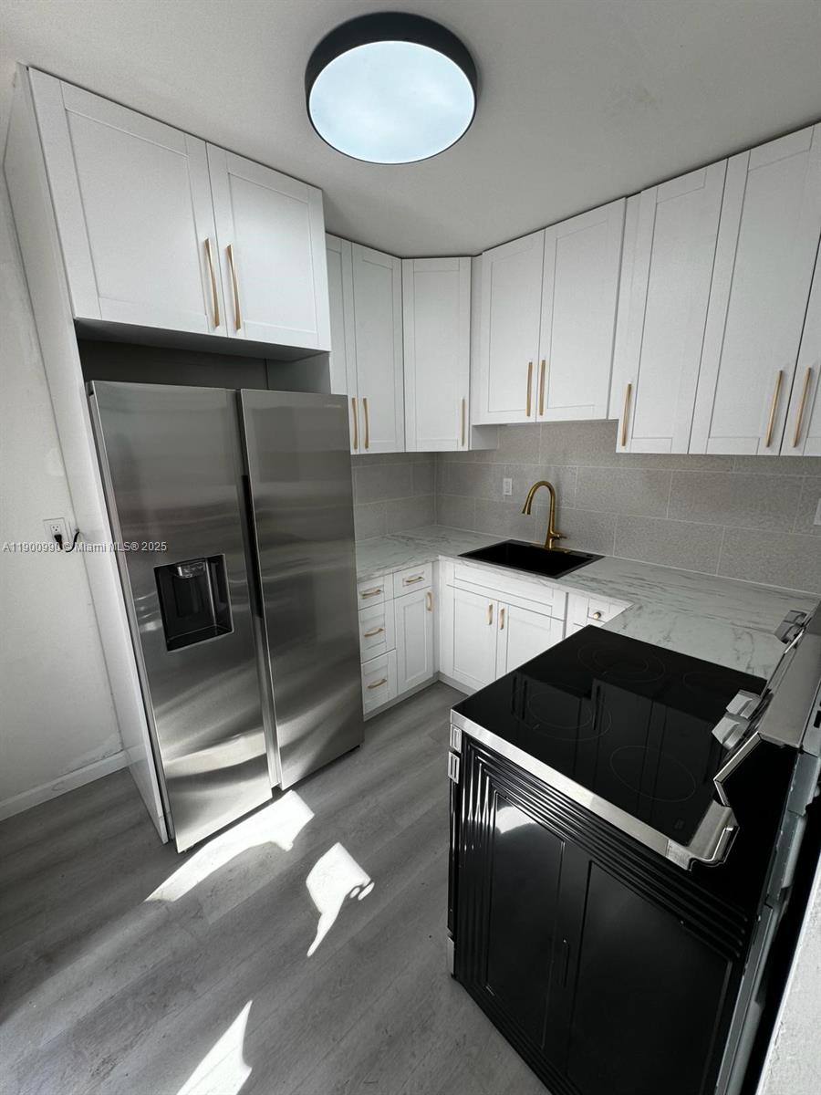 602 Southwest 13th Avenue, Unit 4 Miami, FL 33135 - Photo 7 of 13 a kitchen with granite countertop a refrigerator a sink and a stove