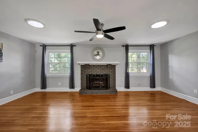 a view of a livingroom with a fireplace a ceiling fan and window