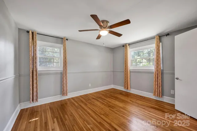 a view of empty room with wooden floor and fan