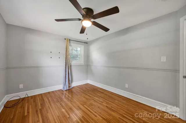 an empty room with ceiling fan and wooden floor