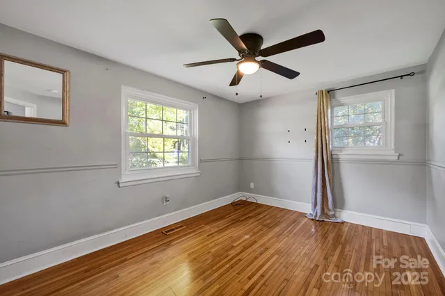 a view of a big room with wooden floor and windows