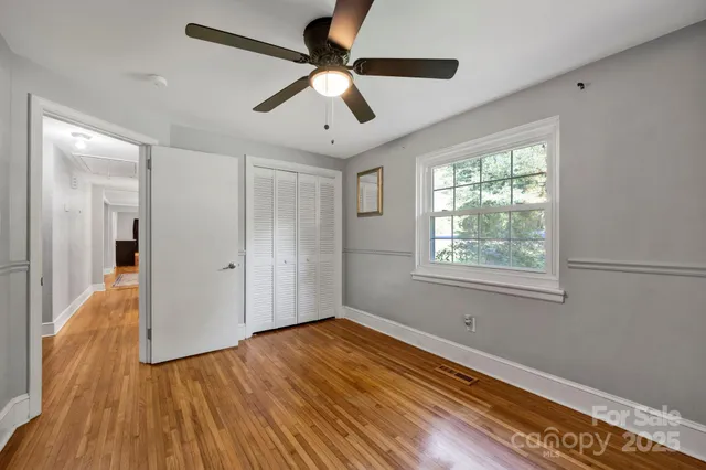 a view of empty room with wooden floor and fan