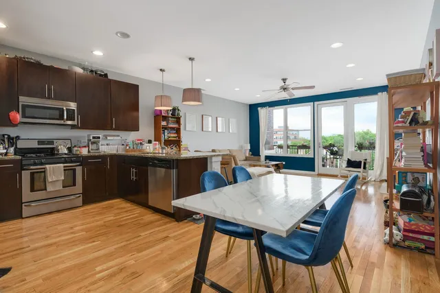 a kitchen with stainless steel appliances granite countertop a stove top oven a sink a dining table and chairs with wooden floor