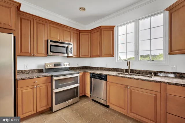 a kitchen with granite countertop white cabinets sink and stainless steel appliances