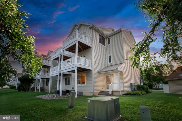 a front view of a house with a garden and lake view
