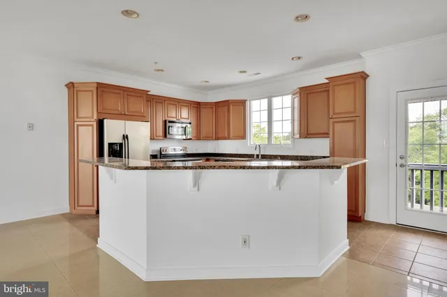 a kitchen with granite countertop a refrigerator a stove a sink and a window